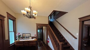 Ein geräumiger Korridor mit einer Holztreppe und einem Kronleuchter.