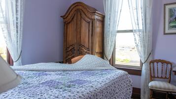 Un dormitorio con cama, un armario de madera, una silla y una ventana con cortinas.