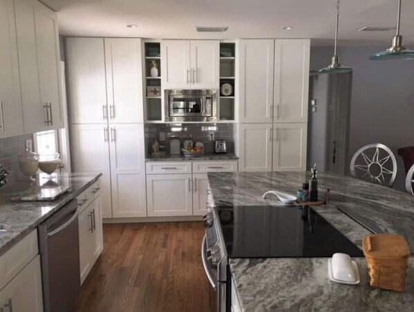 A modern kitchen with white cabinets, a black countertop, and a wooden floor. - Beautiful Coastal Beach Home - 2 min walk to Beach- 4 bedroom 3 bath 2 masters!
(Neptune Beach)