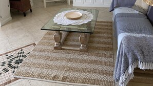 A living room with a glass coffee table, a TV, a white cabinet, and a wicker chair. - Diano Marino / Rollo 100sqm 4 pers. quiet with sea view (Andora)