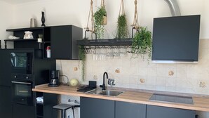 A modern kitchen with black cabinetry, a Bosch oven, a sink, and a coffee maker. - Diano Marino / Rollo 100sqm 4 pers. quiet with sea view (Andora)