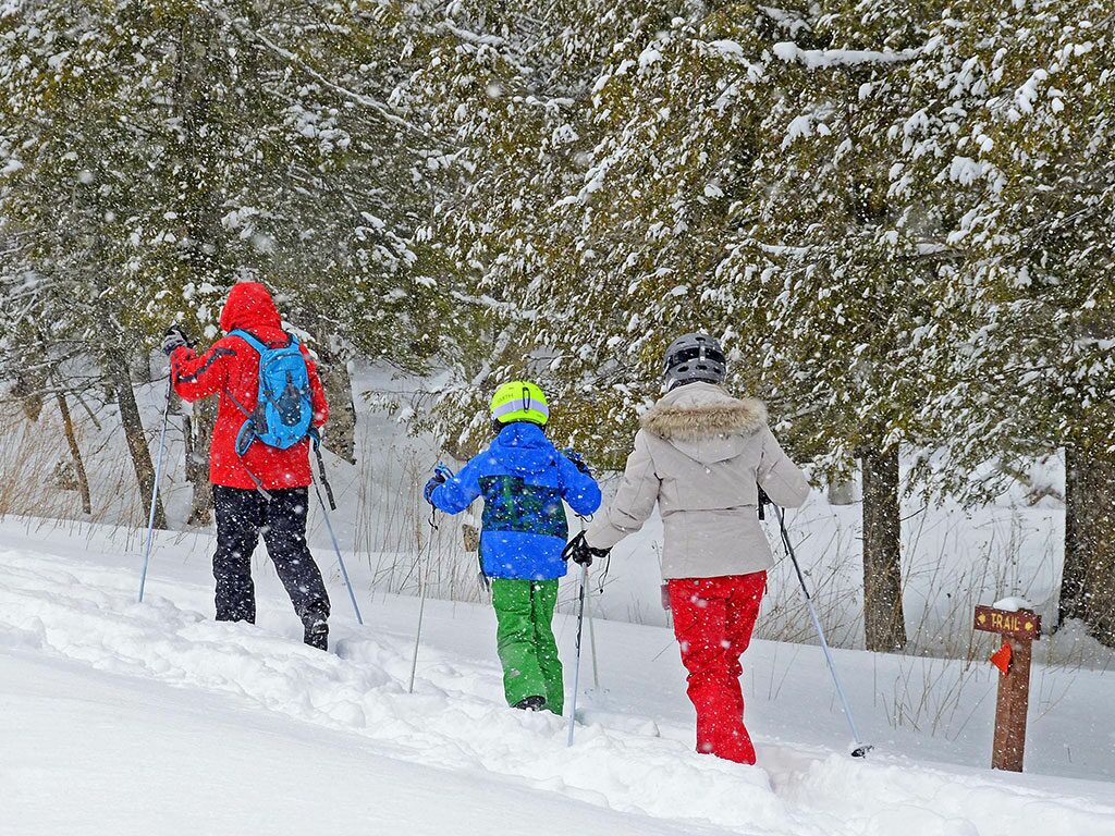Un sendero nevado con tres personas caminando.