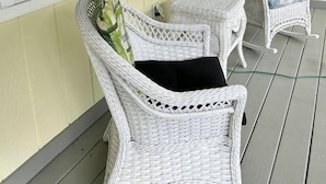 A porch with two wicker chairs and a wicker basket. - Cannon Hill Inn (Rowlesburg)