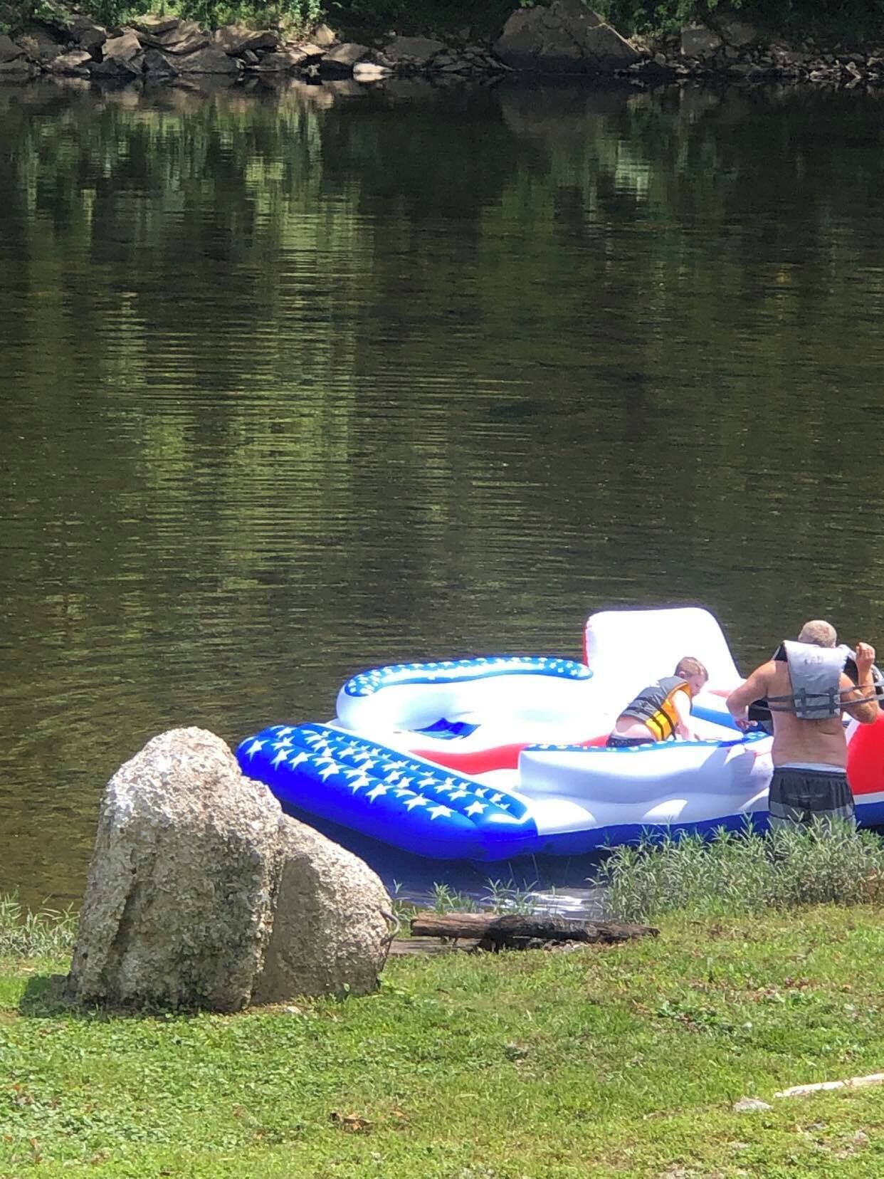 A lake with a blue inflatable raft and a large rock nearby.
