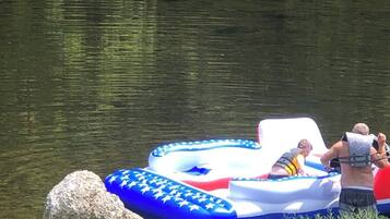 A lake with a blue inflatable raft and a large rock nearby.