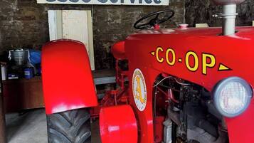 Un tractor rojo con un letrero que dice 'Esso Service' en un taller mecánico.