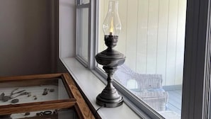 A room with a large window, a display case with artifacts, and a decorative candle holder. - Cannon Hill Inn (Rowlesburg)