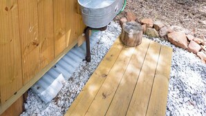 Una baita di legno con un lavandino in metallo e un pontile in legno.