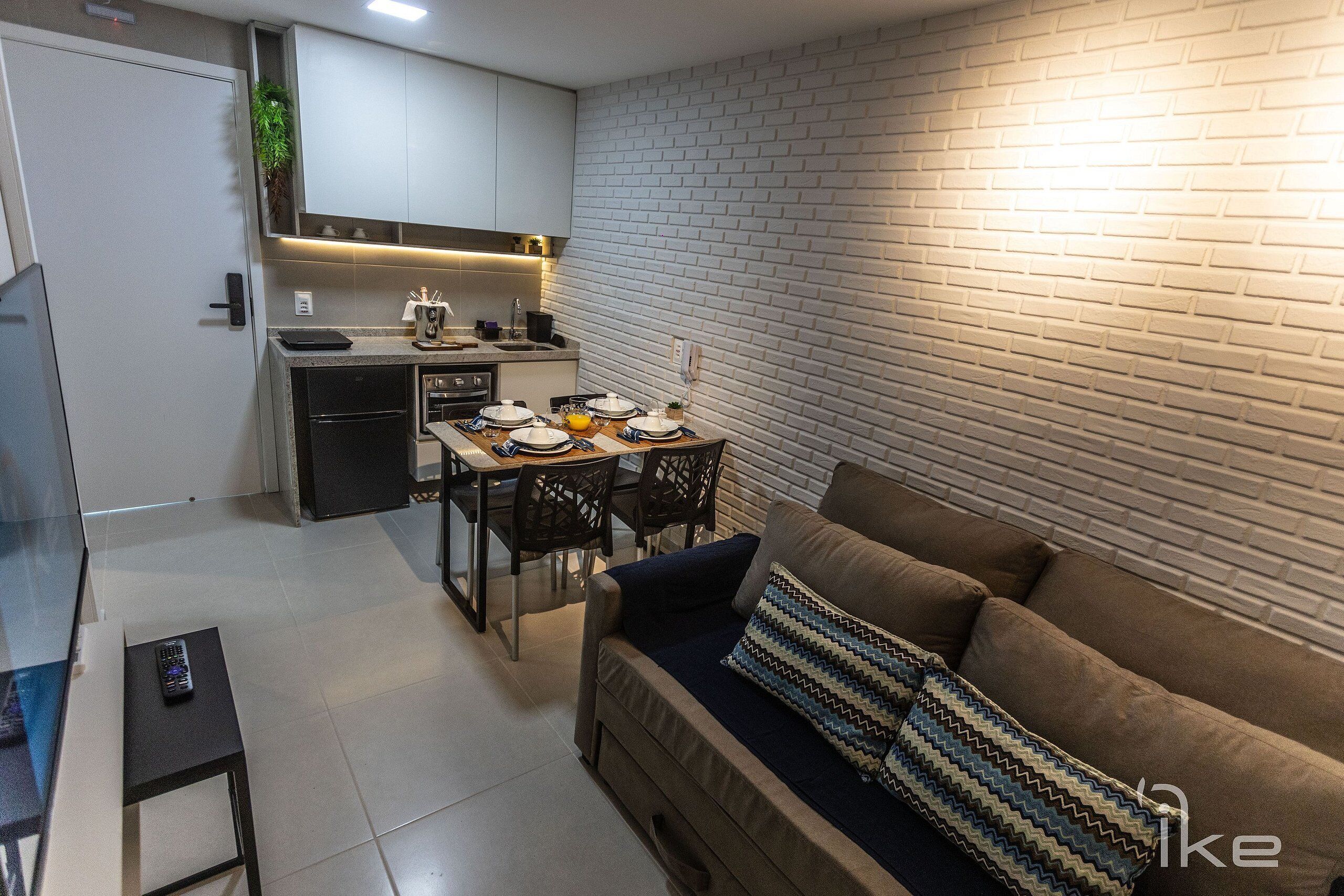 A compact living space with a kitchenette, dining area, and a sofa with a patterned pillow.