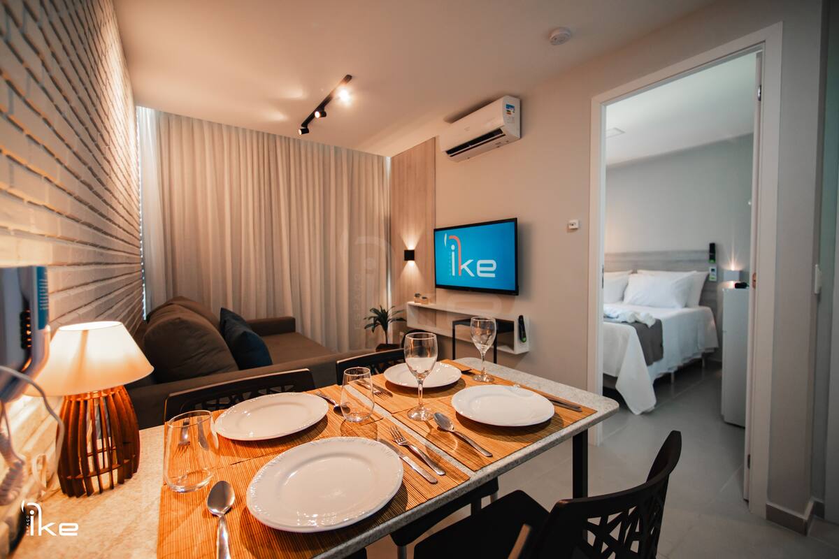 Habitación de hotel con zona de comedor, cama y televisor.