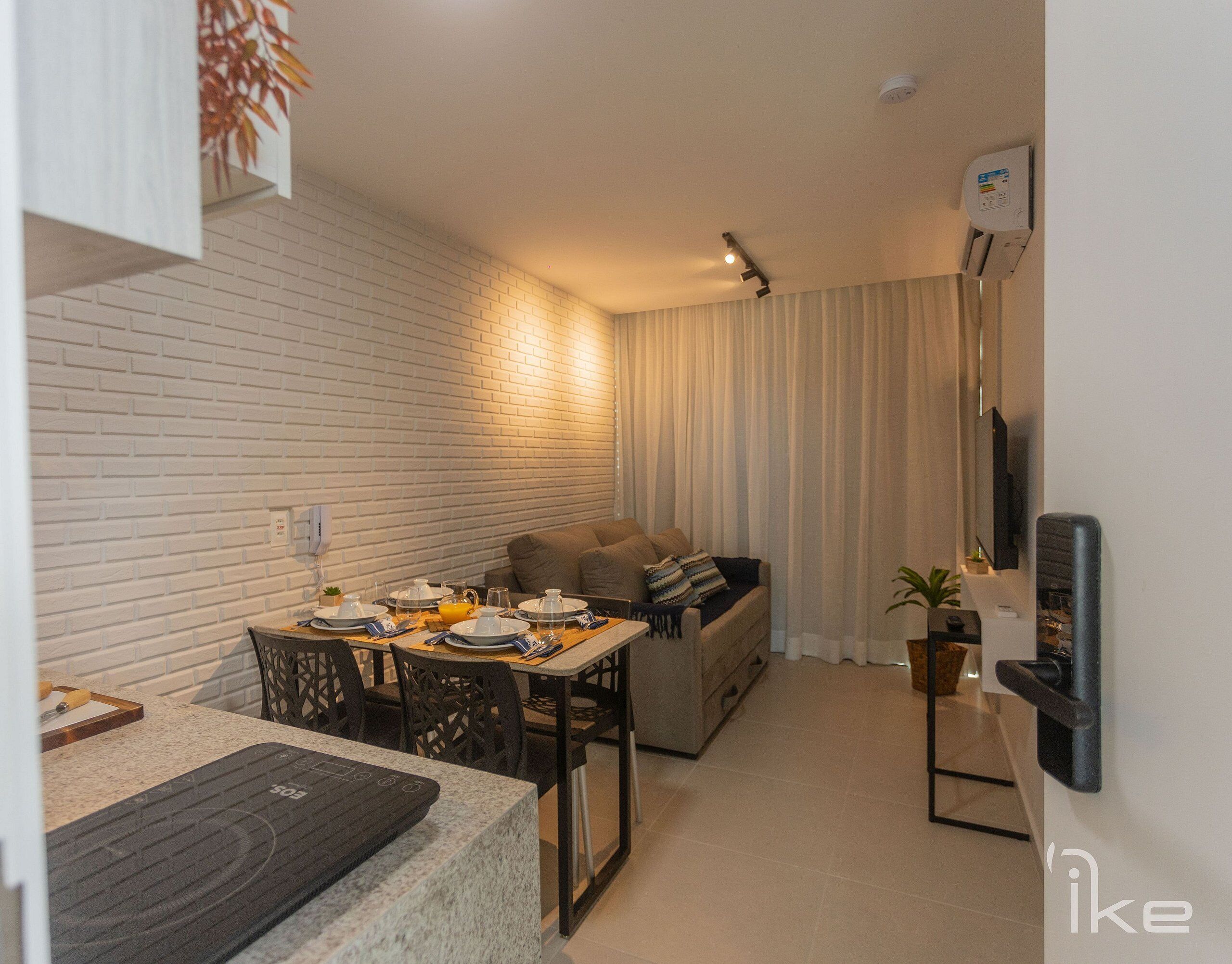 Un espacio habitable compacto con comedor, sofá y televisor montado en la pared.
