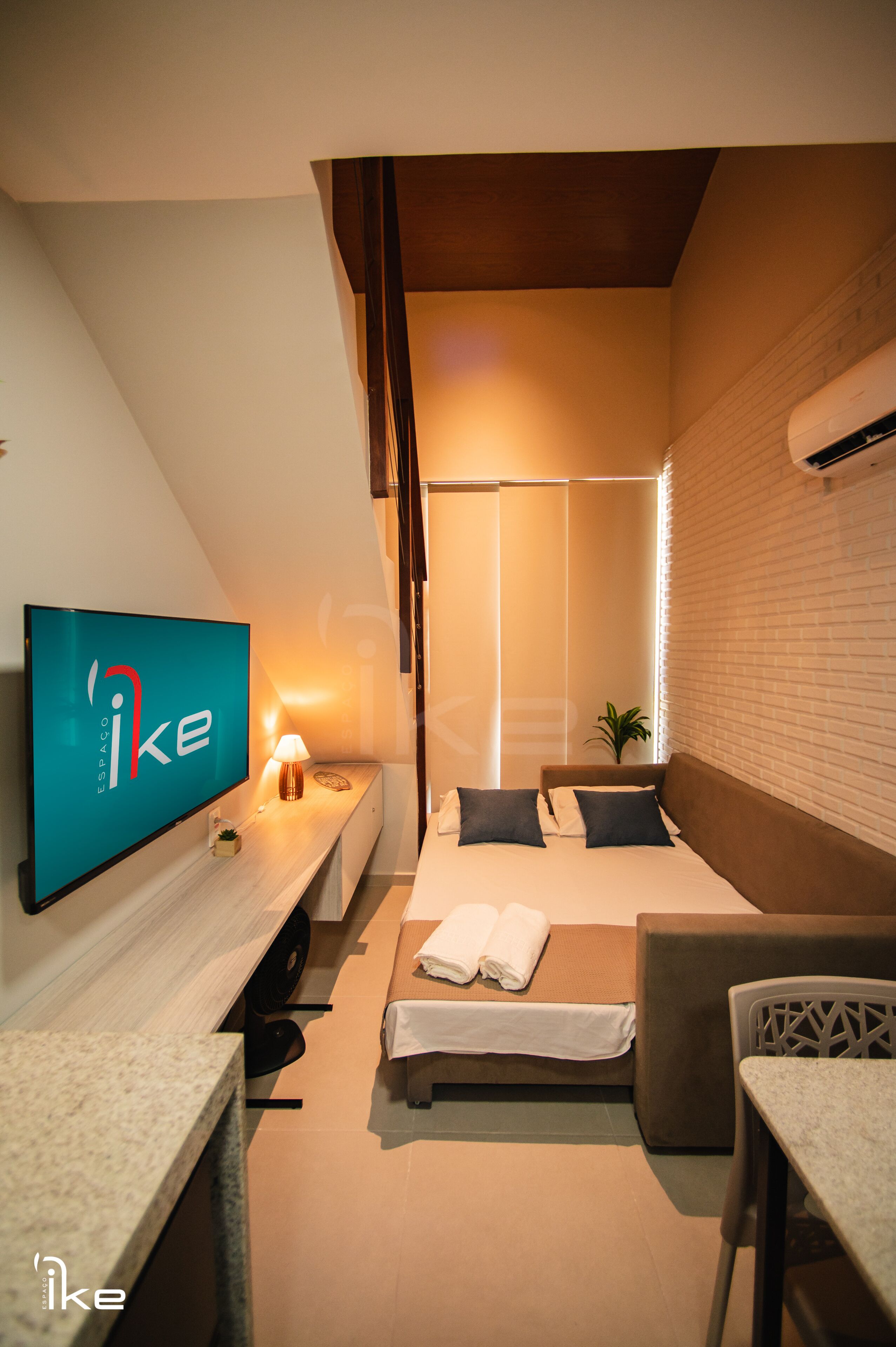 Habitació d'hotel amb llit, escriptori amb televisió, cadira i taula petita.