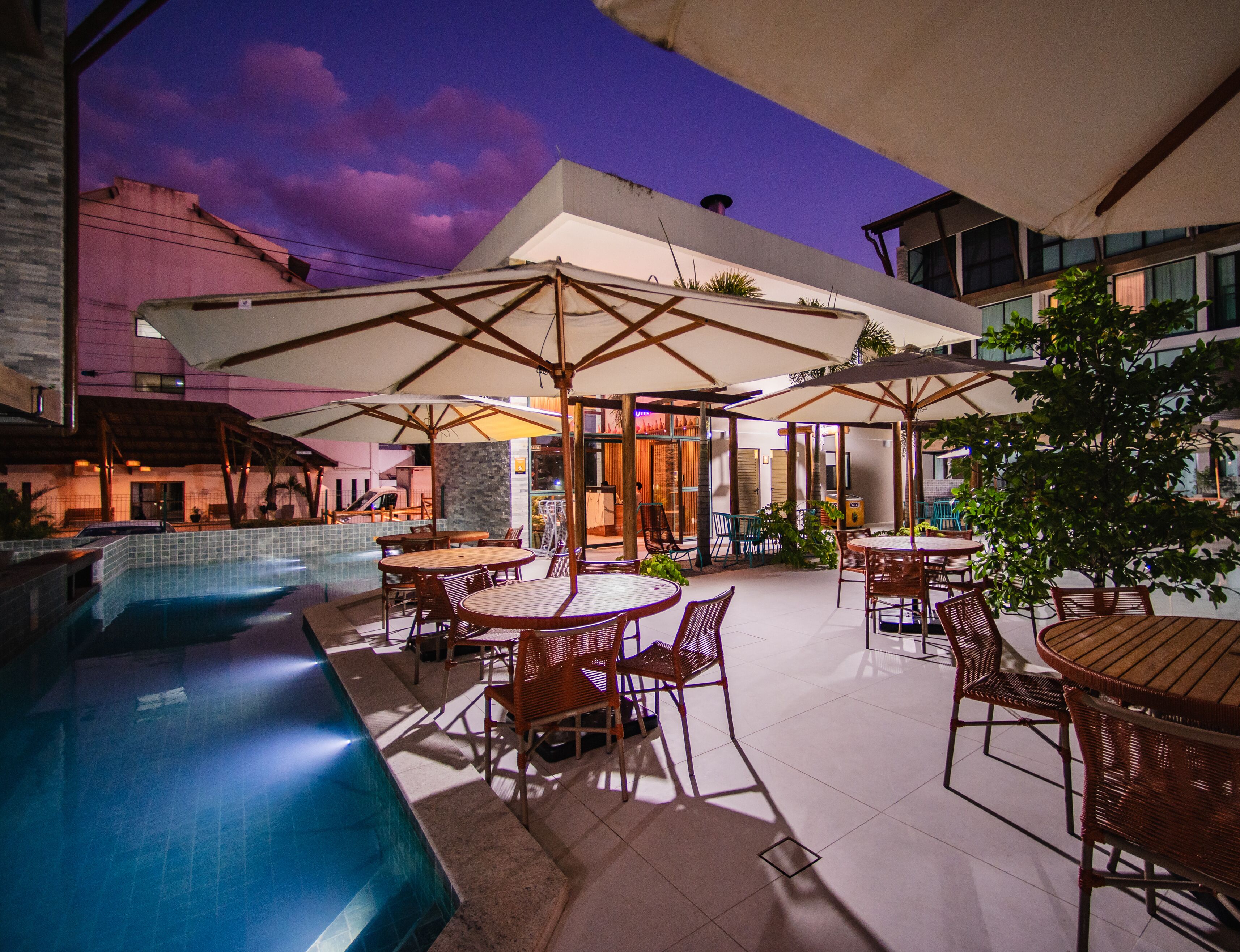 An outdoor patio area with a pool, tables, and umbrellas.