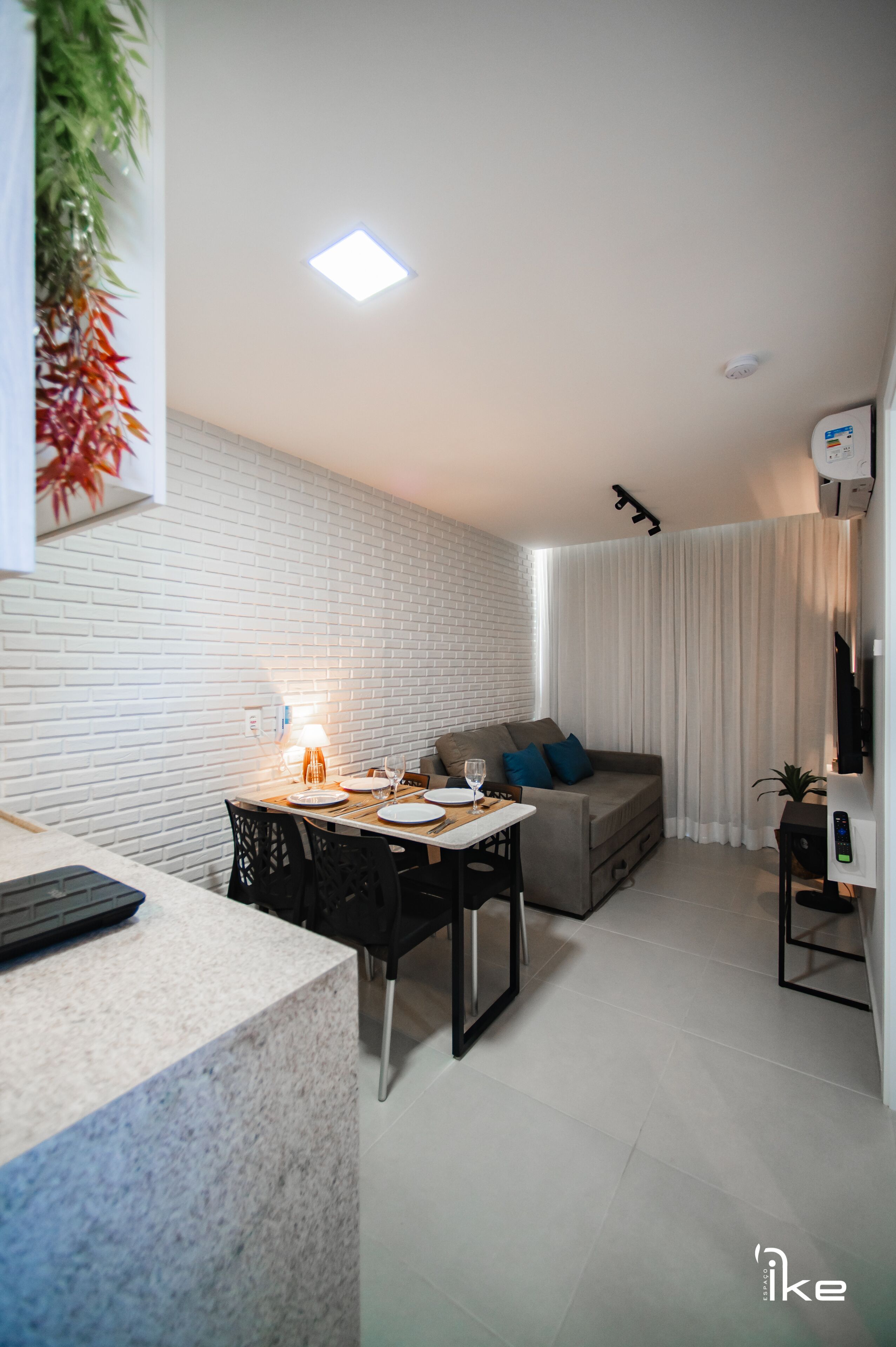 A modern living space with a dining area, a sofa, and a TV.