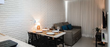 A modern living space with a dining area, a sofa, and a TV.