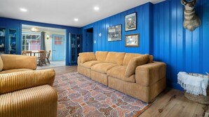 Un salón con una pared azul, una cabeza de animal montada y una alfombra estampada.