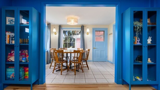Un comedor con una mesa redonda y sillas, flanqueado por estanterías azules.
