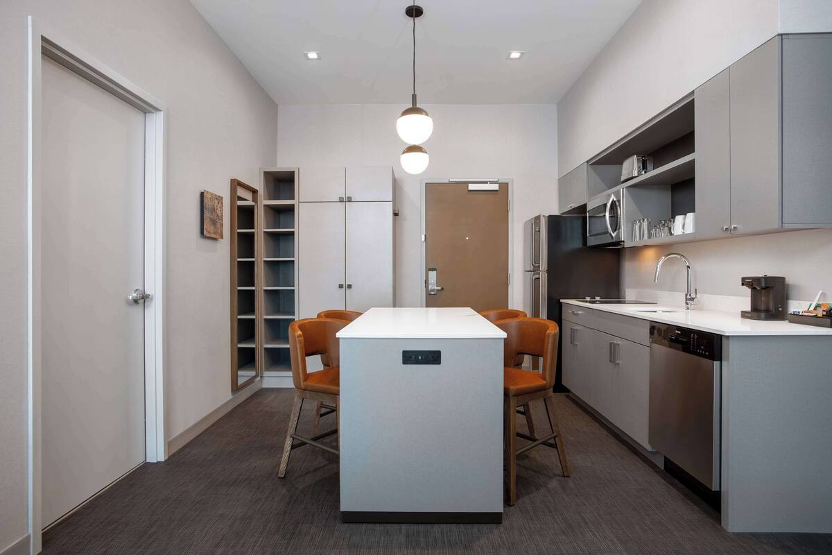 Una cocina moderna con una isla central, electrodomésticos integrados y un comedor con sillas.