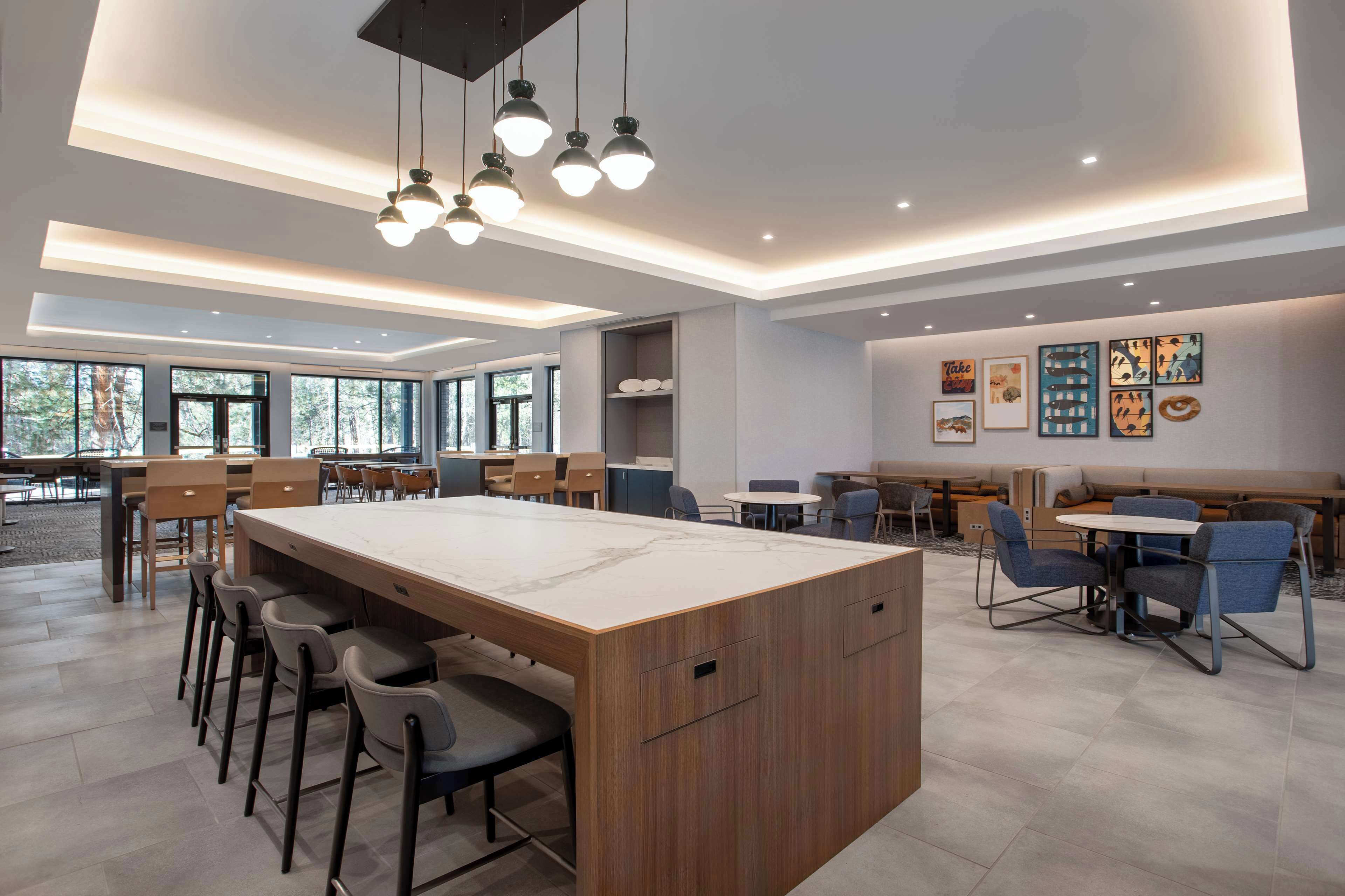 Un comedor moderno con una isla central, taburetes de bar y una variedad de opciones de asientos, incluyendo una cabina y mesas redondas.
