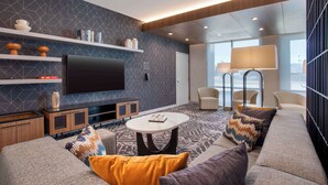 Ein modernes Wohnzimmer mit Flachbildfernseher, Sofas, einem Couchtisch und einem gemusterten Teppich.