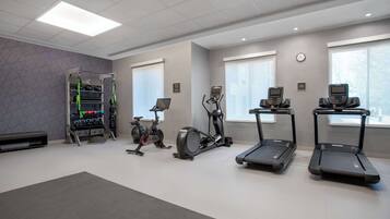 Un gimnasio con cintas de correr, una elíptica y una bicicleta estática.