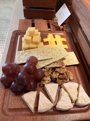 A wooden board with cheese, crackers, grapes, and walnuts. - Hilton Garden Inn Nantong Rudong (Nantong)