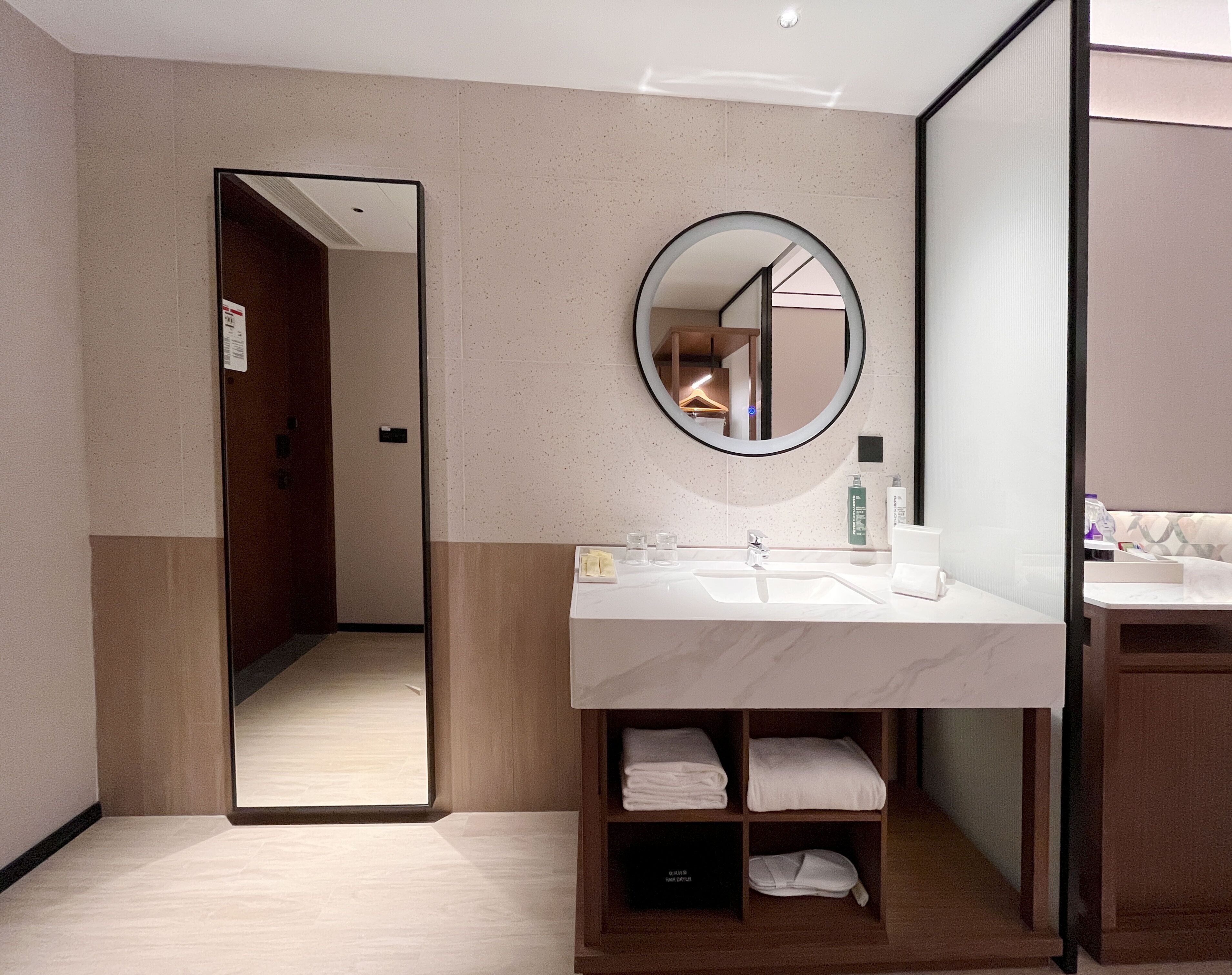 A modern bathroom with a large mirror, a sink, and a towel rack.