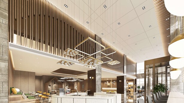 Eine moderne Hotelhalle mit einer zentralen Rezeption, Sitzbereichen und einer hohen Decke mit geometrischen Leuchten.