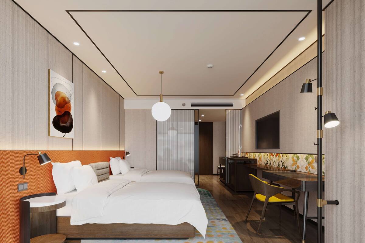 A modern hotel room with a large bed, a desk, a chair, and a TV.