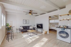 A modern living room with a sofa, coffee table, TV, and a ceiling fan.