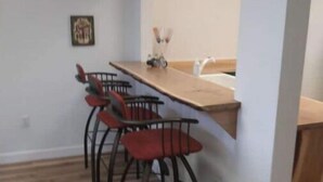Ein Essbereich mit einem langen Holztisch und vier schwarzen Stühlen mit roten Kissen.