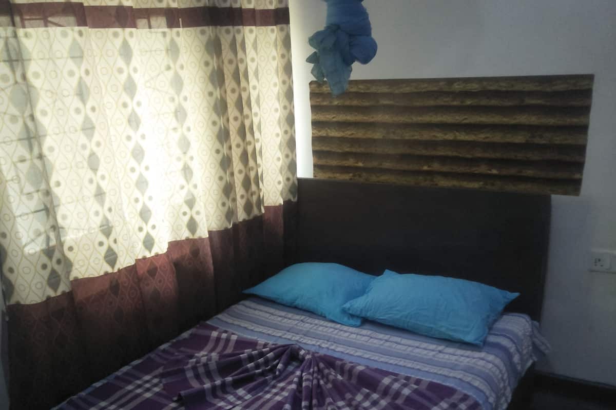 A bed with a checkered blanket, a blue pillow, and a mosquito net above.