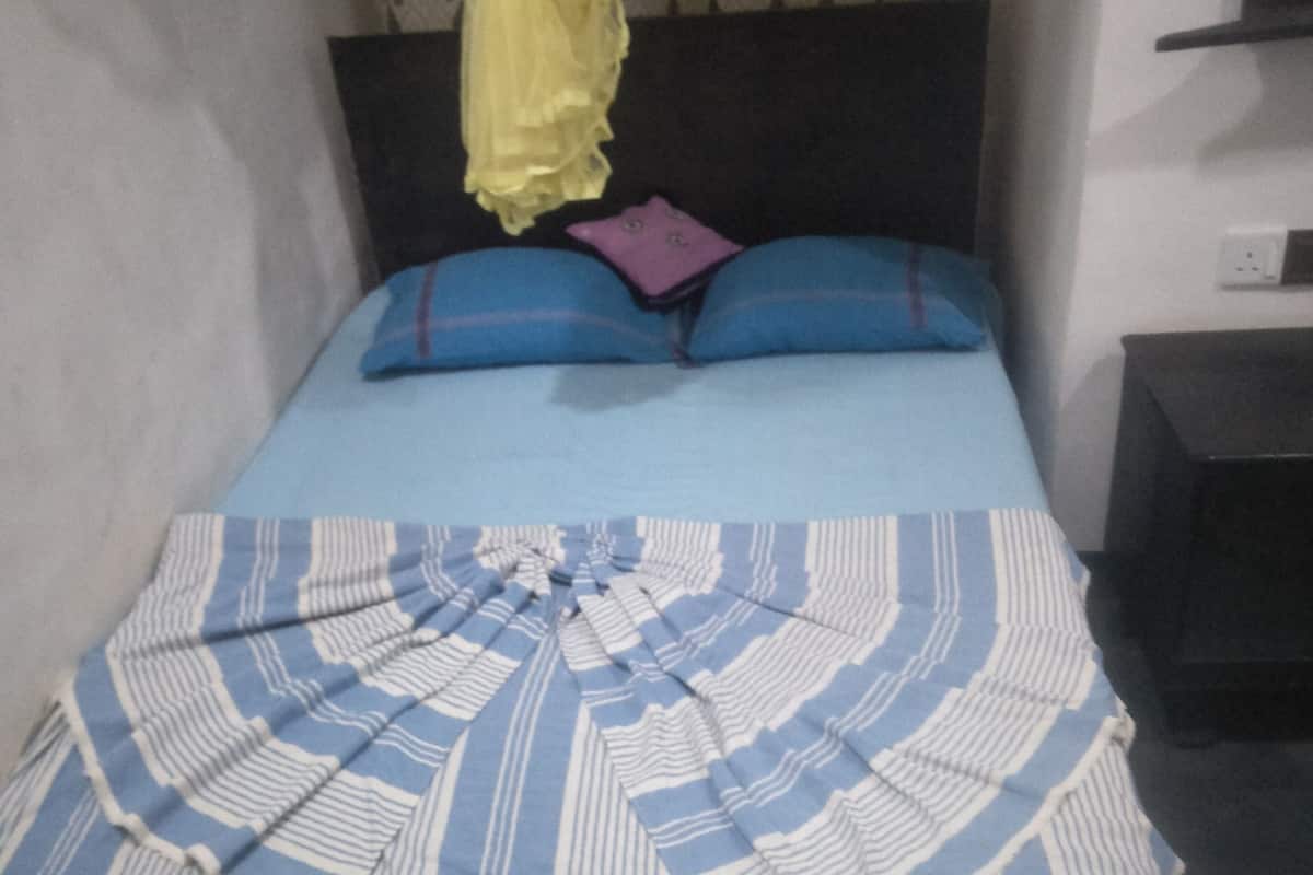 A bed with a blue and white striped bedspread, two blue pillows, and a yellow canopy.