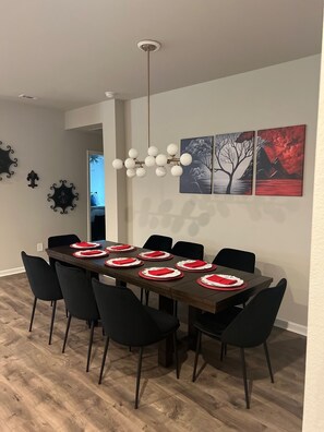Formal dining area with a table for six, featuring a chandelier and framed artworks.