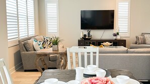 Ein modernes Wohnzimmer mit Essbereich, einem wandmontierten Flachbildfernseher und einer gemütlichen Sitzecke.
