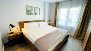 Ein Hotelzimmer mit einem großen Bett, einem Holzkopfende, zwei Nachttischen mit Lampen sowie einem Beistelltisch und einem Fenster mit Vorhängen.