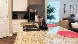A kitchen with granite countertops, stainless steel appliances, and a red rug. - Spacious Home Base with Private Office—Perfect for Remote Work (Lake Charles)