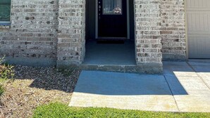 A house with a stone facade, a dark front door, and a garage door. - Spacious Home Base with Private Office—Perfect for Remote Work (Lake Charles)