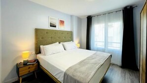 A neatly made bed with white linens, a green upholstered headboard, and a bedside table with a lamp. - Casa SoHo y Alex, Apartment 2A,- 2 bedroom (Estepona)
