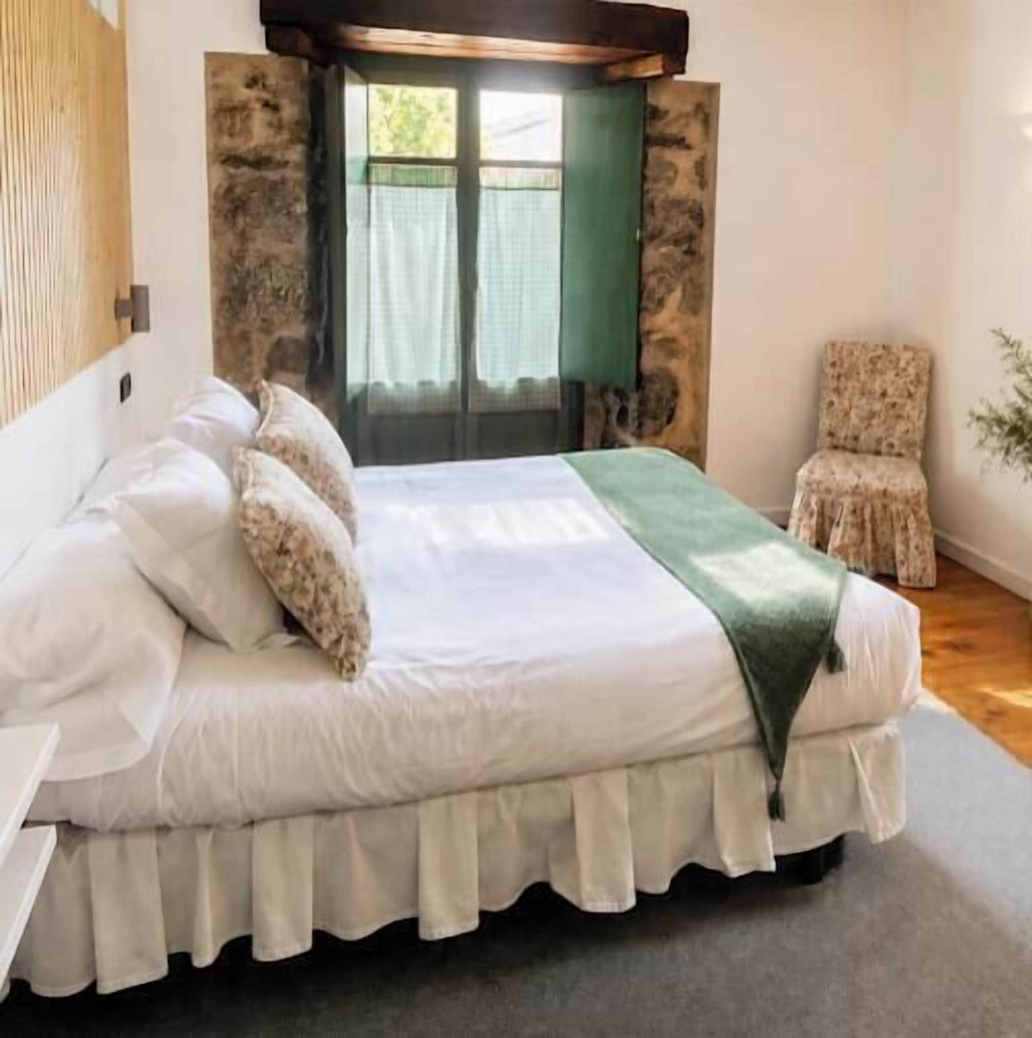 A bedroom with a bed, a chair, a window, and a door.