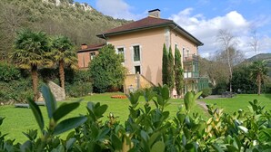 A two-story house with a well-maintained lawn and a stone wall. - La Villa de Palacios (Voto)