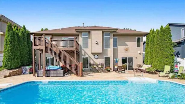 Ein zweistöckiges Haus mit Swimmingpool, einer überdachten Terrasse und einer Treppe, die zu einer Terrasse führt.
