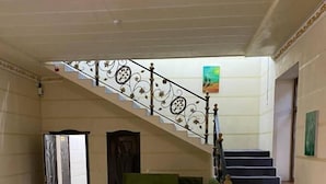 A spacious lobby with a staircase, a green sofa, and a small table. - Green Apple Hotel (Tashkent)