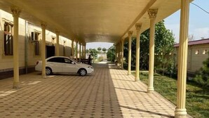 A covered walkway with hexagonal patterned flooring, columns, and a parked car. - Green Apple Hotel (Tashkent)