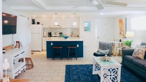 Una cocina moderna con una isla central, taburetes de bar y un comedor con mesa y sillas.