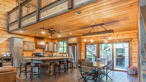 A spacious kitchen with a large island, wooden ceiling, and a view to the outside. - 5Br cabin with private exterior bar and secret cinema from bunk room! (Broken Bow)