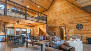 A spacious log cabin interior with a dining area, kitchen, and a cozy living room with a sofa and a coffee table. - 5Br cabin with private exterior bar and secret cinema from bunk room! (Broken Bow)