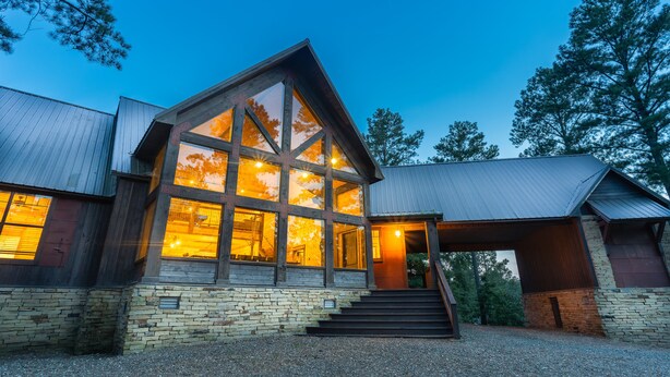 A modern building with large windows, a stone foundation, and a metal roof. - 5Br cabin with private exterior bar and secret cinema from bunk room! (Broken Bow)