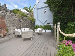 A wooden deck with wicker furniture and potted plants. - Coastal View (Lyme Regis)