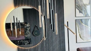 A modern dining area with a round table, two chairs, a wall-mounted clock, and abstract art. - Green High-end Apartment Close to Metro, Uno-city, E-parking, Pool, Gym, Sauna (Vienna)